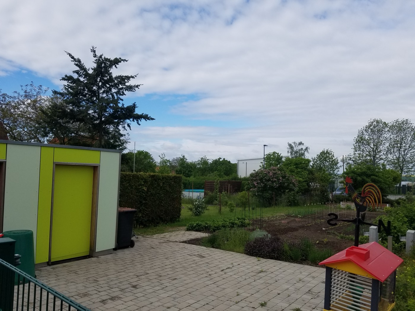 Schulgarten mit Hochbeeten und grünem Geräteschuppen